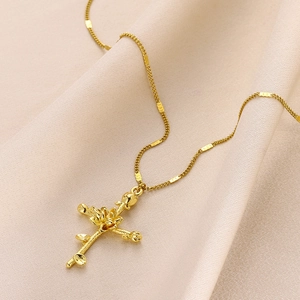 Detailed shot of golden cross pendant necklace with embossed floral patterns on silk fabric