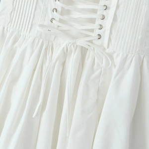 Detail of white corset dress with adjustable back lace-up ribbons and metal eyelets