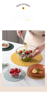 Detail showing hand placing glass bowl on yellow silicone placemat with floral edge
