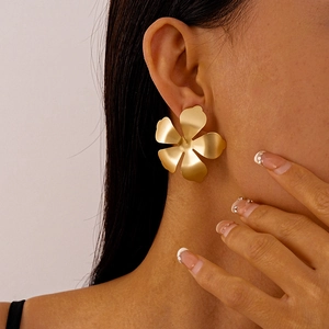 Close-up of matte gold flower earrings worn to show fashion scale and artistic style