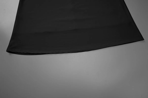 Detailed view of the soft black fabric hemline and ruching texture on the evening dress