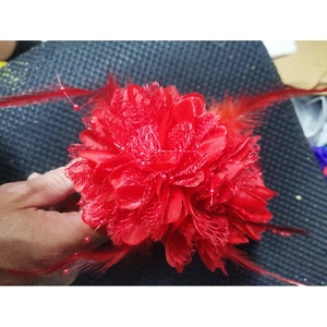 Close-up of red mesh flower headpiece featuring delicate lace petals and elegant feathers