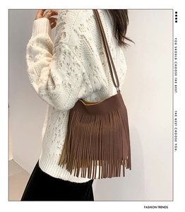 Detailed shot of brown litchi leather bag with bohemian long tassels on white sweater