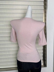 Rear view of pink slim-fit knit top featuring padded shoulders on a female mannequin