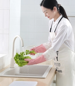 Pink flamingo pattern cleaning gloves being used to wash lettuce in a bright kitchen