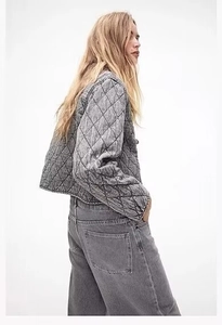 Vista laterale posteriore di una giacca di jeans trapuntata grigio scuro con cuciture a rombi