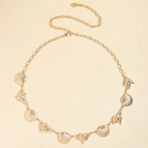 Detailed view of a golden vintage starfish and shell body chain on a textured background