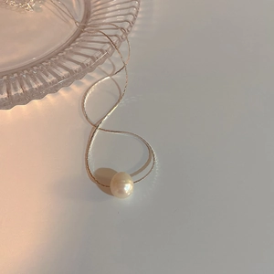Close-up of minimalist silver chain necklace featuring a single round white pearl pendant