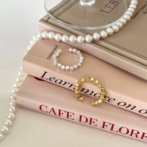 Elegant beaded ear cuffs in gold and silver finish on a stylish book display