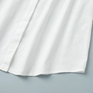 Close-up of white linen shirt dress hem showcasing high-quality fabric texture and stitching