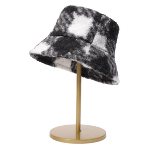 Plush black and white checkered bucket hat on a gold stand with warm fleece texture