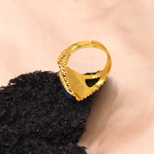 Detailed macro view of an open gold ring featuring a blue gemstone and intricate filigree work