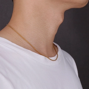 Close-up of minimalist gold titanium steel corn chain necklace on female neck