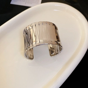 Detail shot of irregular silver cuff bracelet with geometric pleated texture on white tray