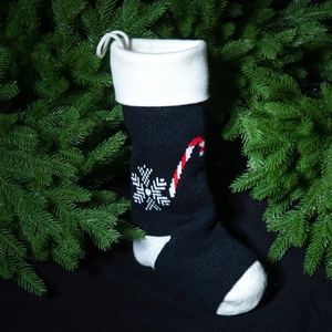 Knitted Christmas stocking with candy cane and snowflake patterns on pine branches