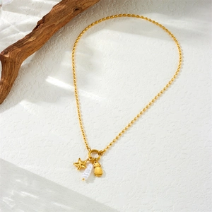 Gold beaded chain necklace with starfish, pineapple charms and baroque pearl on white background