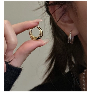 Close-up of minimalist S925 silver U-shaped crescent huggie earrings in gold and silver