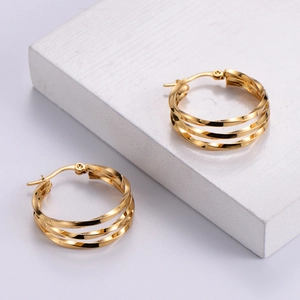 Macro view of triple-layered spiral gold hoop earrings with a polished mirror finish