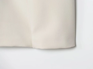 Gros plan sur la texture du tissu sergé blanc cassé et les coutures de ce tailleur cintré