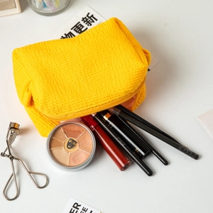 Macro shot of yellow pleated bubble fabric makeup bag with brushes and eyelash curler