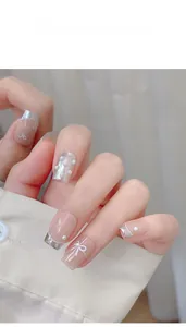 Macro detail of white mermaid pearls, bow charms, and micro beads for nail art design