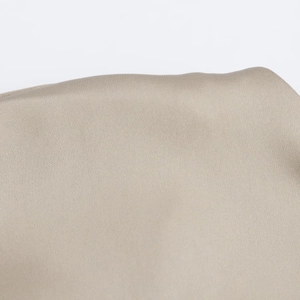 Gros plan du tissu satiné plissé élégant en beige avec une finition brillante