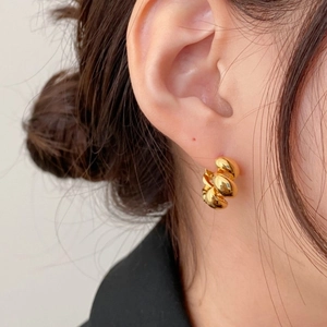 Close-up of twisted gold rope earrings on ear for minimalist style demonstration