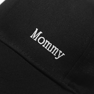 Close-up of white Mommy embroidery on a black cotton twill baseball cap