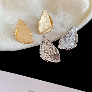 Detailed view of hammered metal triangle earrings in gold and silver finishes