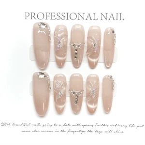 Detailed view of nude pink cat-eye press-on nails with rhinestones and butterfly art
