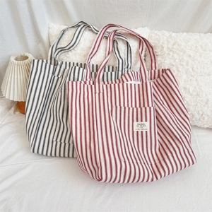Detail of striped canvas tote bags in red and blue colors on a cozy bed background