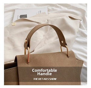 Detail view of the comfortable brown suede handbag handle with gold U-shaped metal hardware