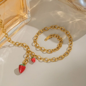 Detail of 18K gold stainless steel chain with red strawberry pendants and S.STEEL stamp