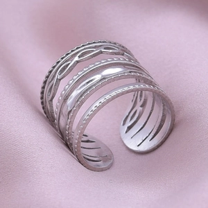 Detailed close-up of multi-layer geometric stainless steel ring on purple satin fabric