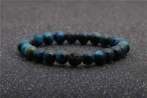 Macro shot of blue tiger eye beads and one black lava stone bead on a beaded bracelet