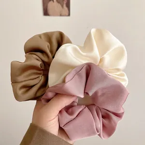 Three-piece set of elegant satin hair scrunchies in caramel, cream, and dusty pink colors