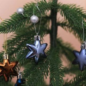 Blue and bronze star ornaments hanging on green Christmas tree branches in close-up view