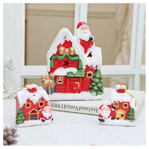Detailed view of red ceramic Christmas village ornaments with faux snow and gold bows