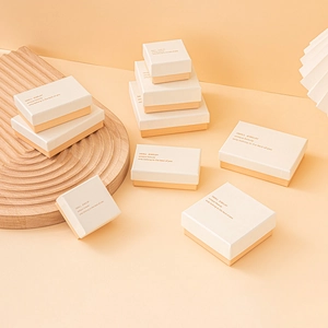 Close-up of beige and gold textured jewelry gift boxes with gold foil typography