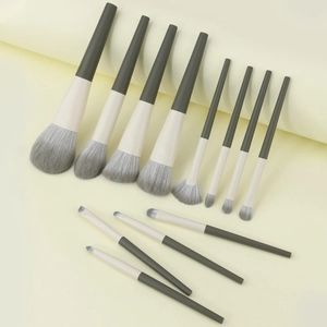 Flat lay of 12-piece travel makeup brush set with dark green handles and soft bristles
