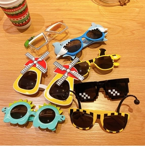 Close-up of various creative cartoon sunglasses for children on a wooden table