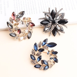 Three elegant crystal floral brooches in black, colorful, and blue gemstone patterns