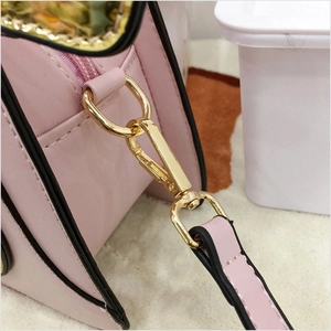 Detail of pink PU leather handbag showing golden metal hooks and precise stitching
