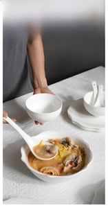 Detail of white ceramic tableware set with elegant embossed patterns and wavy edges