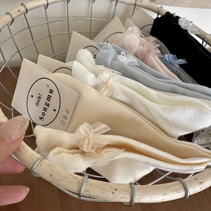 Detailed view of assorted pastel cotton socks with delicate organza ribbon bows in a basket
