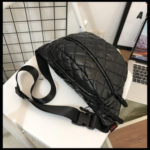 Close-up of black quilted waist bag with adjustable strap on a chair