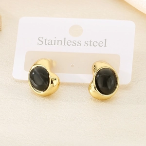 Detailed macro shot of gold stainless steel stud earrings with black cat-eye stones