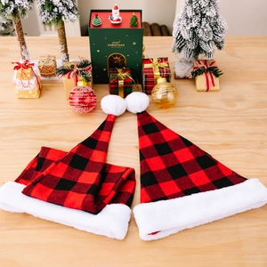 Classic red and black plaid Christmas hat with white faux fur trim on a festive wooden table