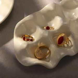 Macro shot of vintage gold rings with red gemstone and textured metal on ceramic tray