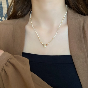Detailed shot of ethnic beaded necklace with white stones and water drop pendant on a model